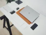 A desk with a laptop computer, phone and smart whatch